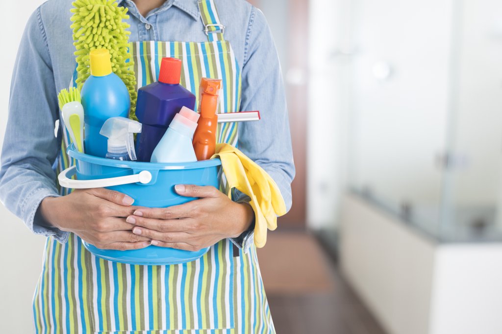 woman with many cleaning equipment ready to clean house on bathroom background