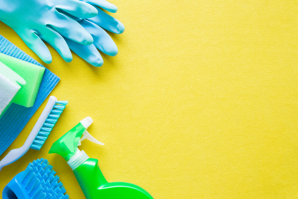 Colorful cleaning set for different surfaces in kitchen, bathroom and other rooms. Empty place for text or logo on yellow background. Cleaning service concept. Early spring regular clean up