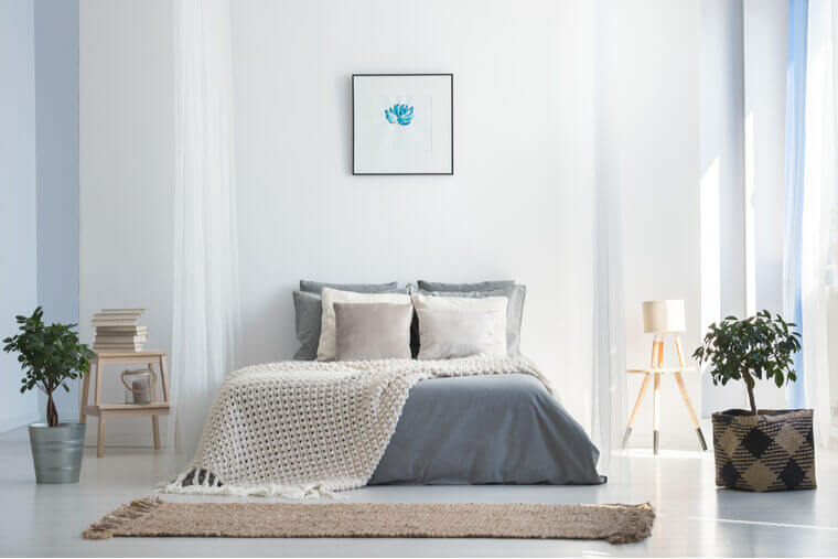 Knit blanket on king-size bed in natural warm bedroom of modern apartment in soft gray and blue colors Knit blanket on king-size bed in natural warm bedroom of modern apartment in soft gray and blue colors