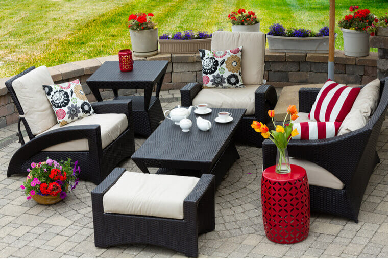 Overview of Upscale Patio Set, Dark Wicker Luxury Furniture with Comfortable Cushions on Outdoor Stone Patio of Affluent Home Overview of Upscale Patio Set, Dark Wicker Luxury Furniture with Comfortable Cushions on Outdoor Stone Patio of Affluent Home