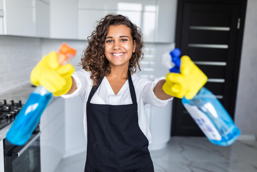 Woman cleaning kitchen. Young woman wearing black apron washing kitchen hood