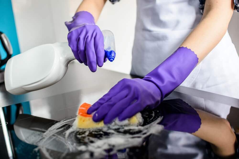 Woman's hands cleaning kitchen top in rubber protective gloves Woman's hands cleaning kitchen top in rubber protective gloves