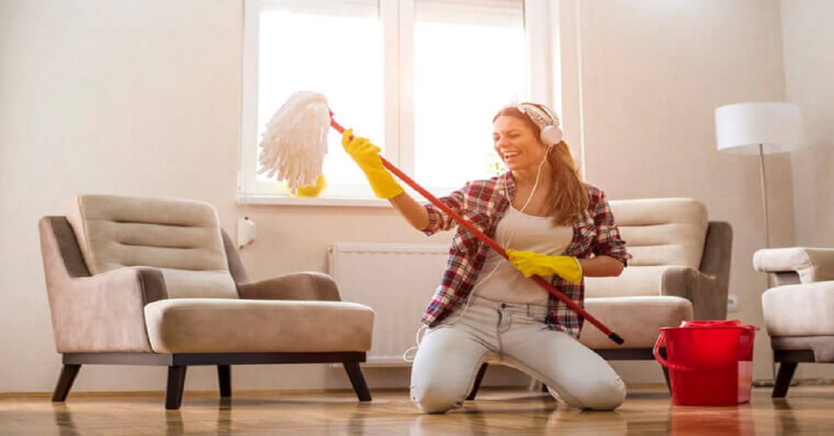 Young woman with headphones and mop ready for home cleaning Young woman with headphones and mop ready for home cleaning