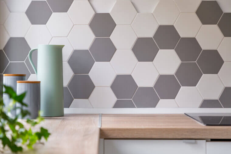 Kitchen with grey and white honeycomb wall tiles and wooden worktop