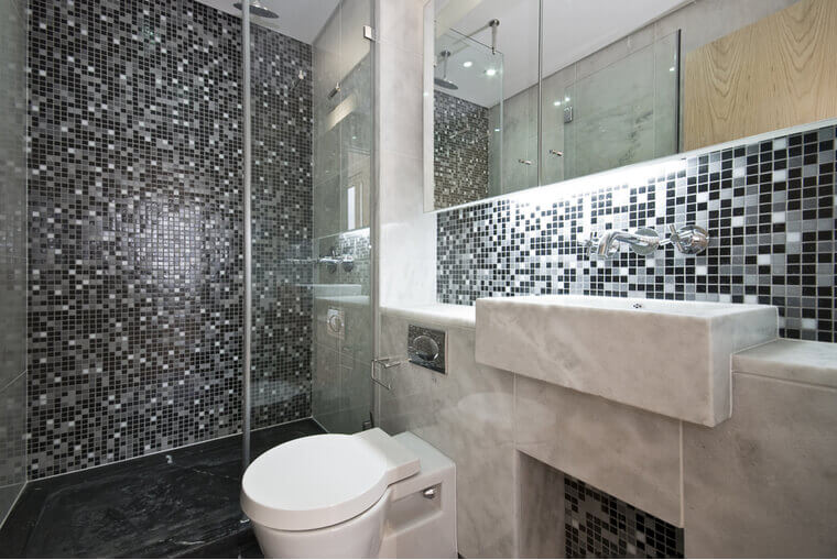 Modern bathroom in black and white with mosaic tiled walls and white ceramic wash basin and toilet Modern bathroom in black and white with mosaic tiled walls and white ceramic wash basin and toilet