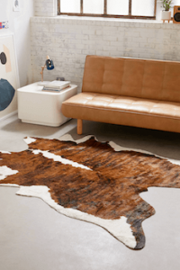 An animal hide rug next to a brown leather sofa