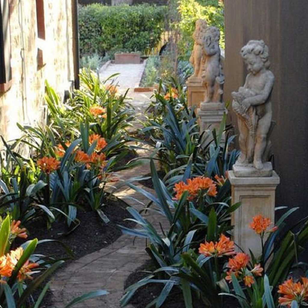 Stone side pathway with flowers and statue Stone side pathway with flowers and statue