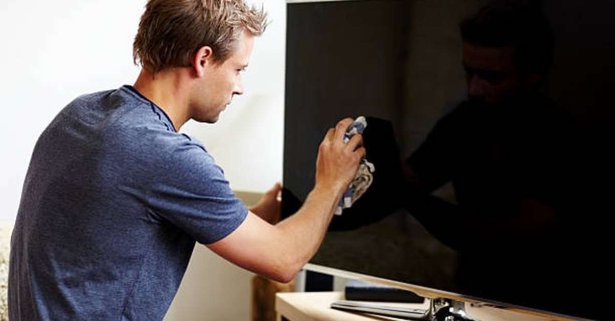 A guy cleaning a flat screen tv A guy cleaning a flat screen tv