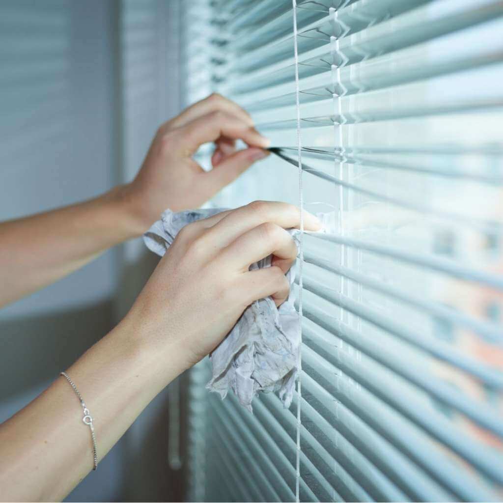a lady cleaning Venetian blind