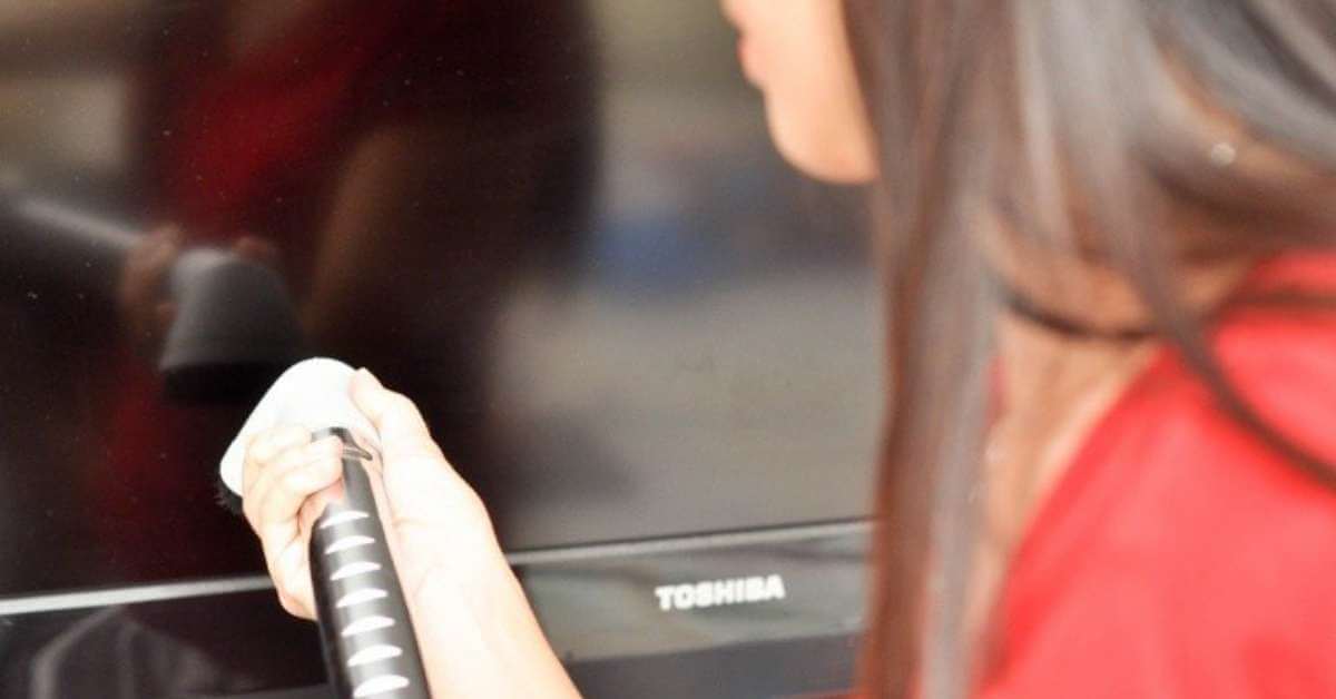 a lady using a vacuum cleaner to clean a plasma screen tv a lady using a vacuum cleaner to clean a plasma screen tv