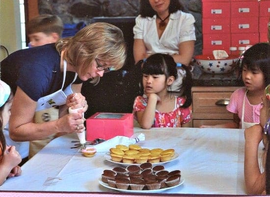 A mom teaching her girls how to decorate cupcakes for birthday party