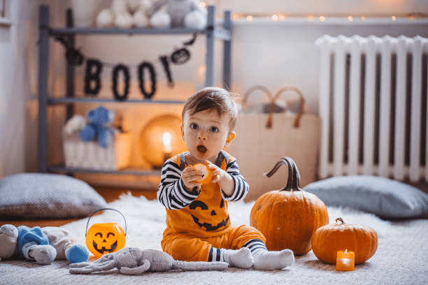 Halloween-themed photoshoot for a toddler in a pumpkin costume