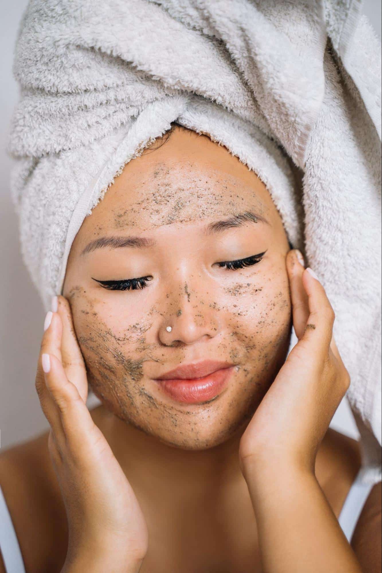 A lady scrubbing her face to remove dead skin cells and impurities